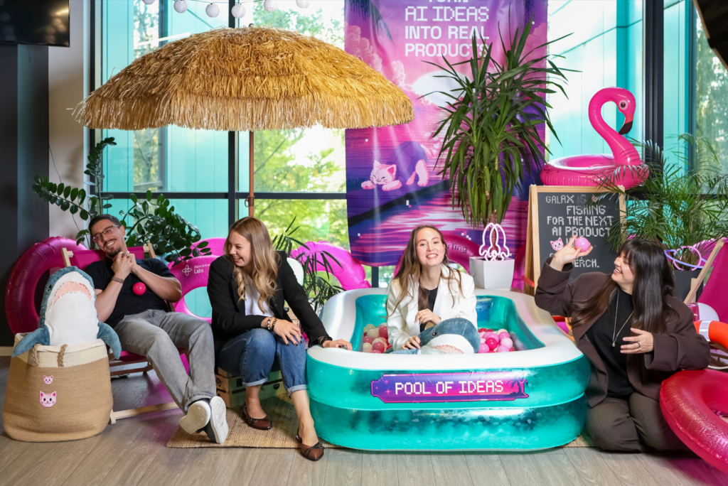 Sigma Software specialists at the Pool of Ideas photo zone of the AI Product Ideas Contest, with an inflatable pool, flamingo and a banner reading Turn AI ideas into real products
